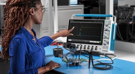 Engineer using a Tektronix oscilloscope and oscilloscope probe to measure a signal on a device under test