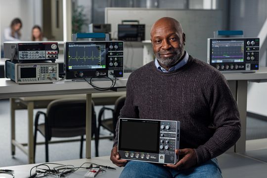 an engineer holds a Tektronix MSO 2 series portable oscilloscope