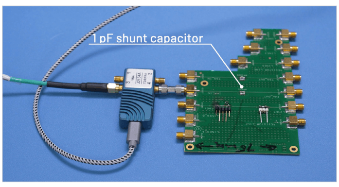 TDR probe connected to a PCB with a 1 pF shunt capacitor soldered midway along a signal trace.