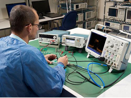 Engineer at test bench using TSG41000A RF signal generator with Tektronix oscilloscope and Keithley power supply
