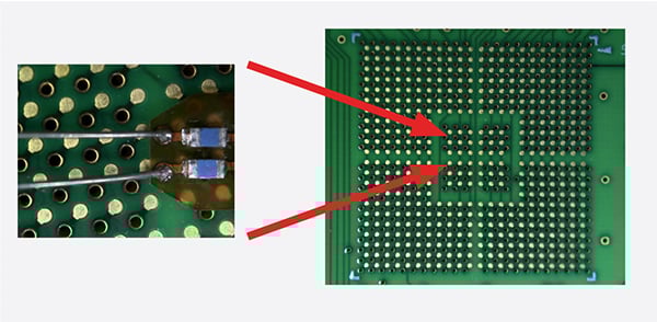 Probe tip and wires next to small test points on the back side of a BGA package.