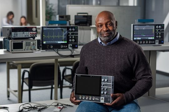 an engineer holds a Tektronix MSO 2 series portable oscilloscope